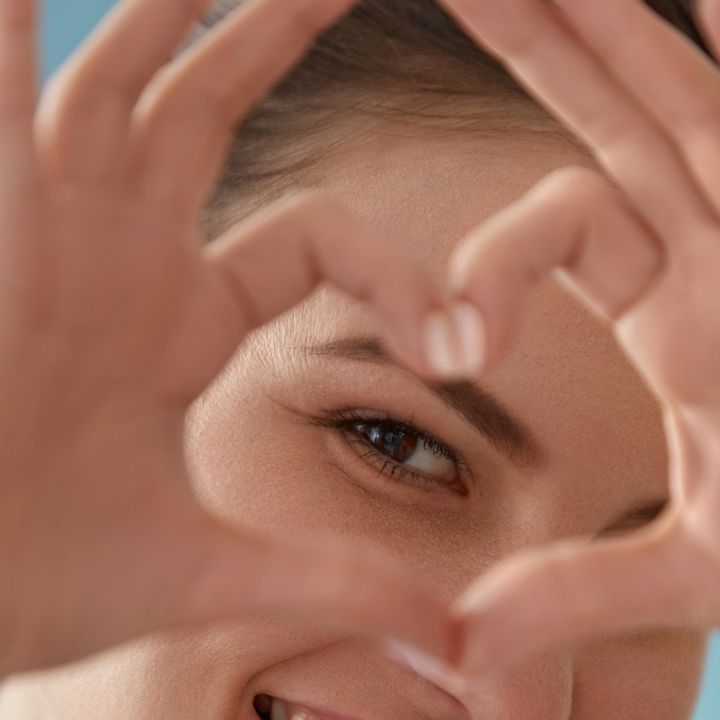 Young Woman showing heart shape around her eye supporting eye health.